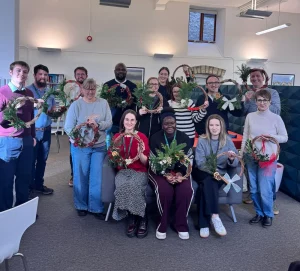 Members of the British Solar Renewables team holding up their wreaths they made during the wreath making workshop held in the office