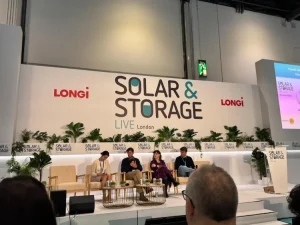 Wide shot of a green field under a blue sky with scattered clouds, showing dual land use for nature and renewable energy.