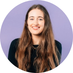 Woman with long brown hair photographed against a purple background