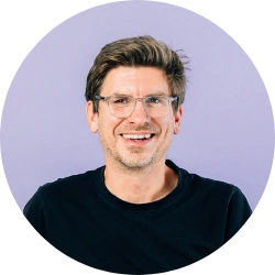 Portrait for a man with brown hair and glasses in a black tshirt against a purple background